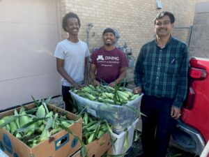Three workers from Pillsbury United Communities accepting sweet corn donation